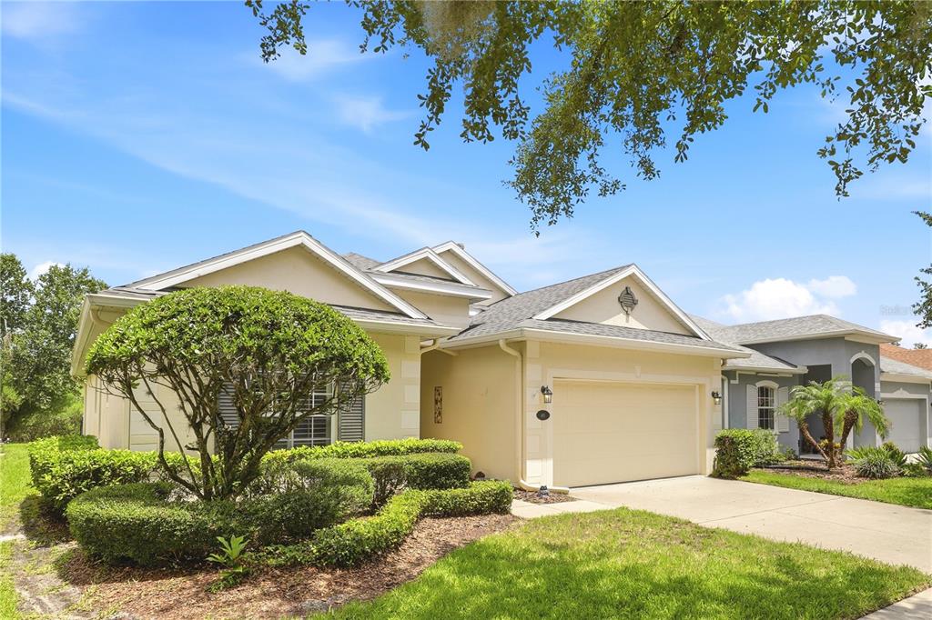 A single-story house with a beige exterior, a two-car garage, and a manicured front lawn — 401 HERON POINT WAY, DELAND, FL