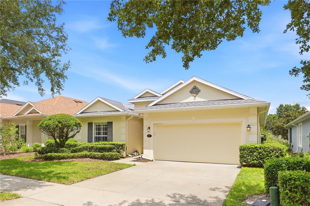 A single-story house with a beige stucco exterior, a two-car garage, and a landscaped yard — 401 HERON POINT WAY, DELAND, FL