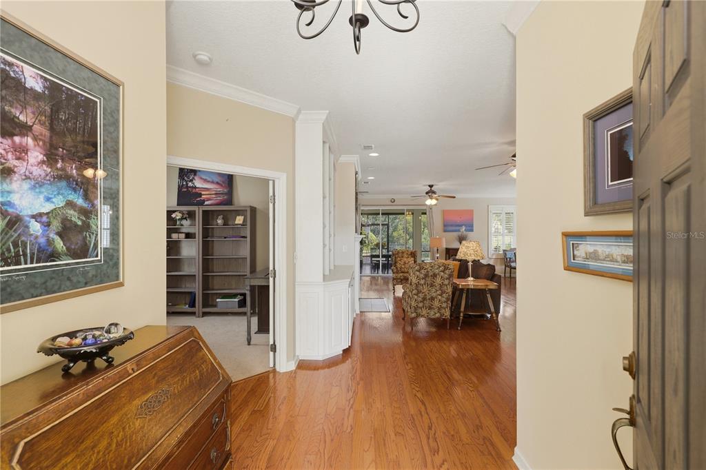 A view from an entryway into a living room with hardwood floors and built-in shelving — 401 HERON POINT WAY, DELAND, FL