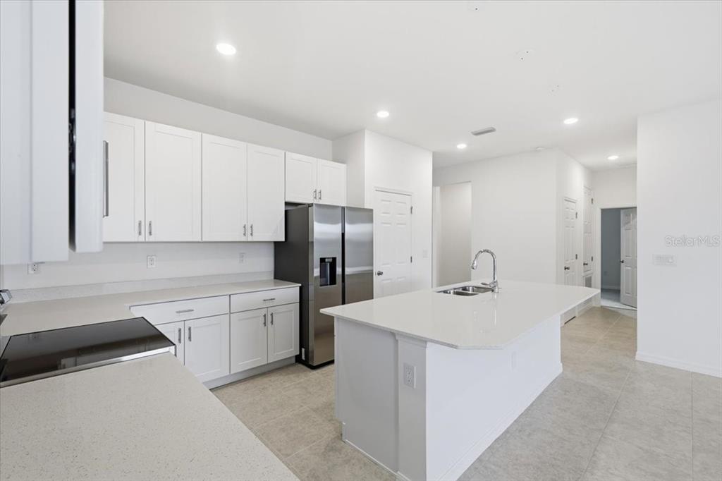 A modern kitchen features white cabinets, stainless steel appliances, and a large central island — 155 BOTTLE BRUSH, HAINES CITY, FL