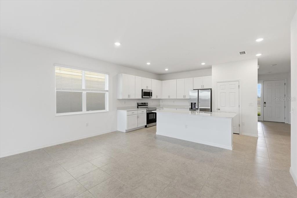 A modern kitchen features white cabinets, stainless steel appliances, and a central island — 155 BOTTLE BRUSH, HAINES CITY, FL