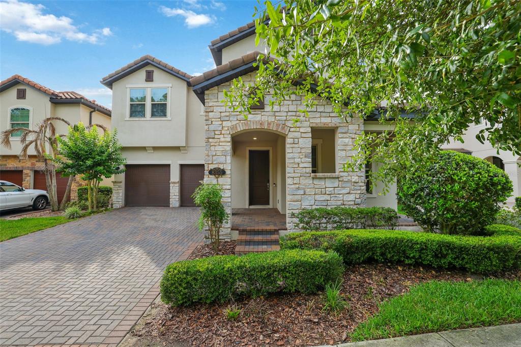 A two-story house features a stone facade, a brick driveway, and a two-car garage — 8355 TORCELLO ISLE DRIVE, WINDERMERE, FL