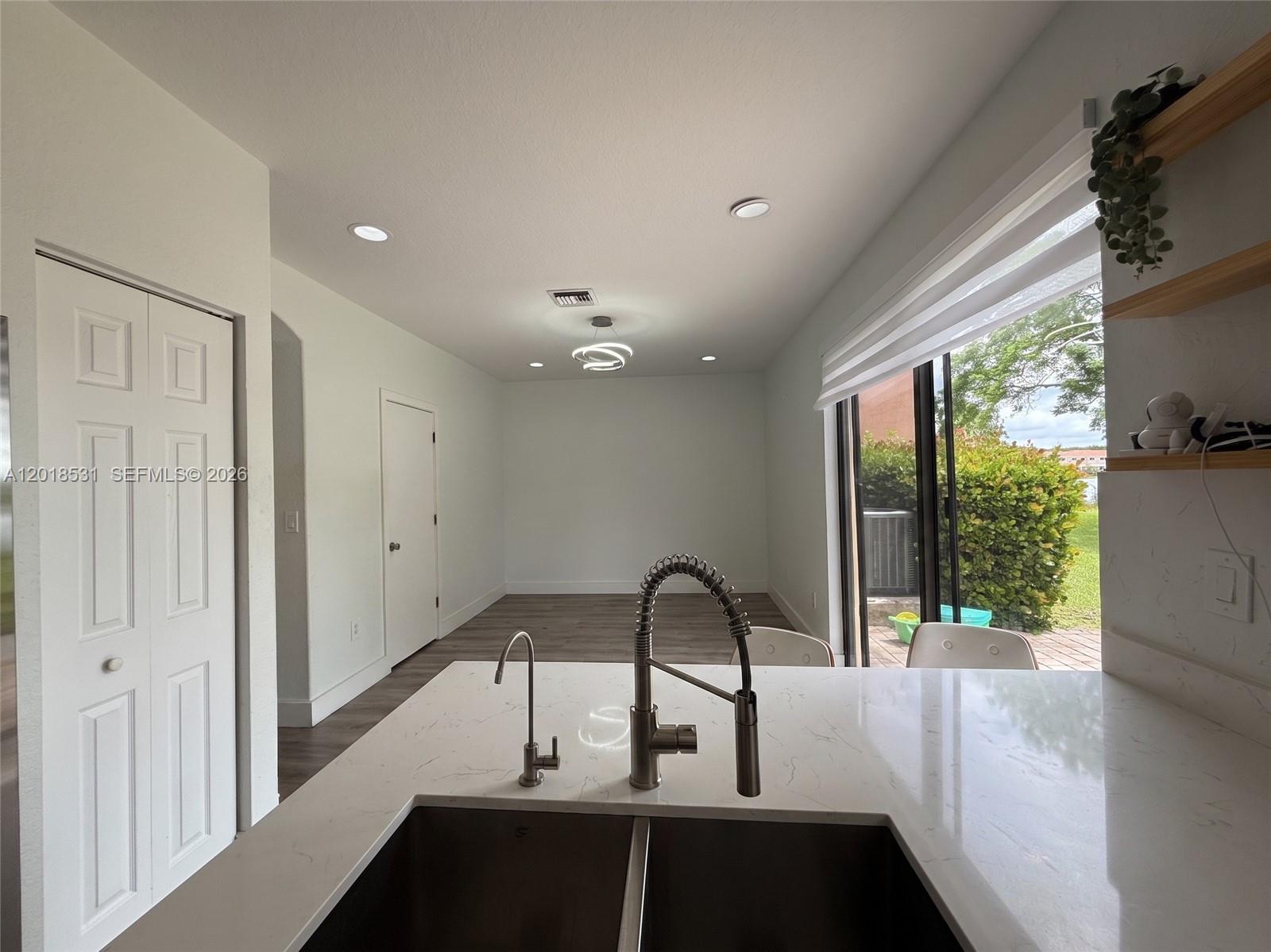 A kitchen island with a double sink overlooks an open living area and patio — 1575 SE 20th Rd, Homestead FL 33035, HOMESTEAD, FL