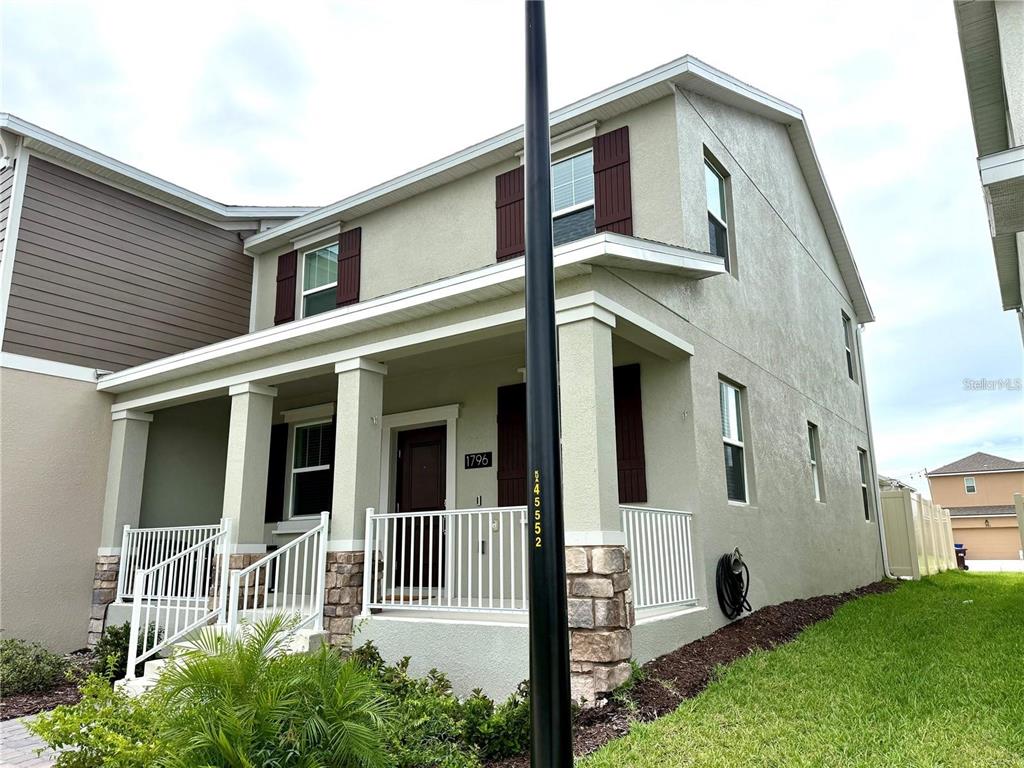 A two-story house with a covered front porch, stone accents, and white railings — 1796 TOHOQUA BOULEVARD, KISSIMMEE, FL