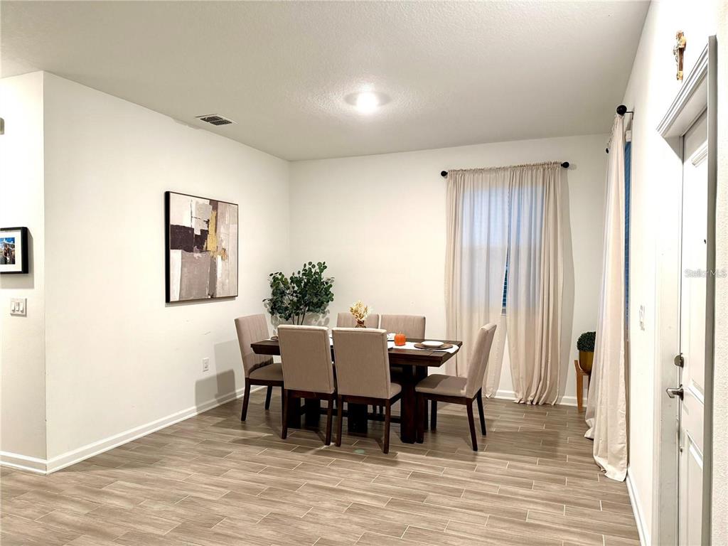 A dining room features a dark wood table with six upholstered chairs and tile flooring — 1796 TOHOQUA BOULEVARD, KISSIMMEE, FL