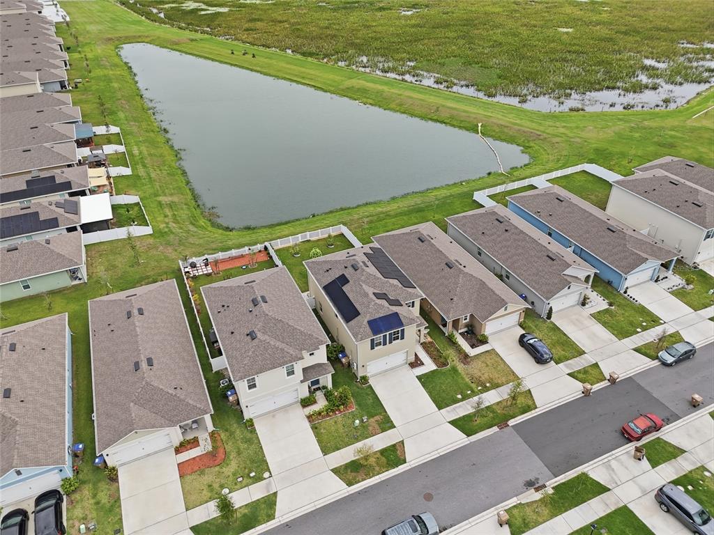 An aerial view shows a suburban neighborhood with houses, a retention pond, and grassy areas — 1777 WALNUT CREEK DRIVE, KISSIMMEE, FL