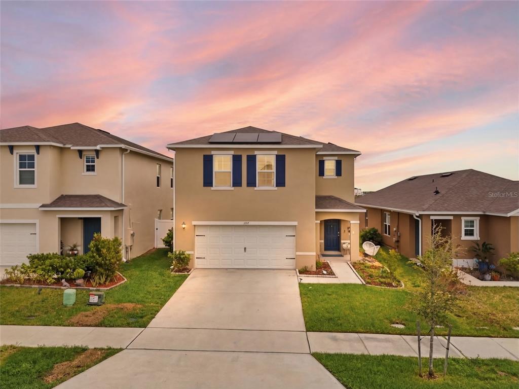 A two-story suburban house with a tan exterior, white garage door, and solar panels — 1777 WALNUT CREEK DRIVE, KISSIMMEE, FL