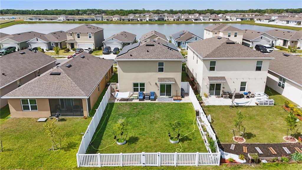 An aerial view shows suburban houses with fenced backyards and a pond in the background — 1777 WALNUT CREEK DRIVE, KISSIMMEE, FL