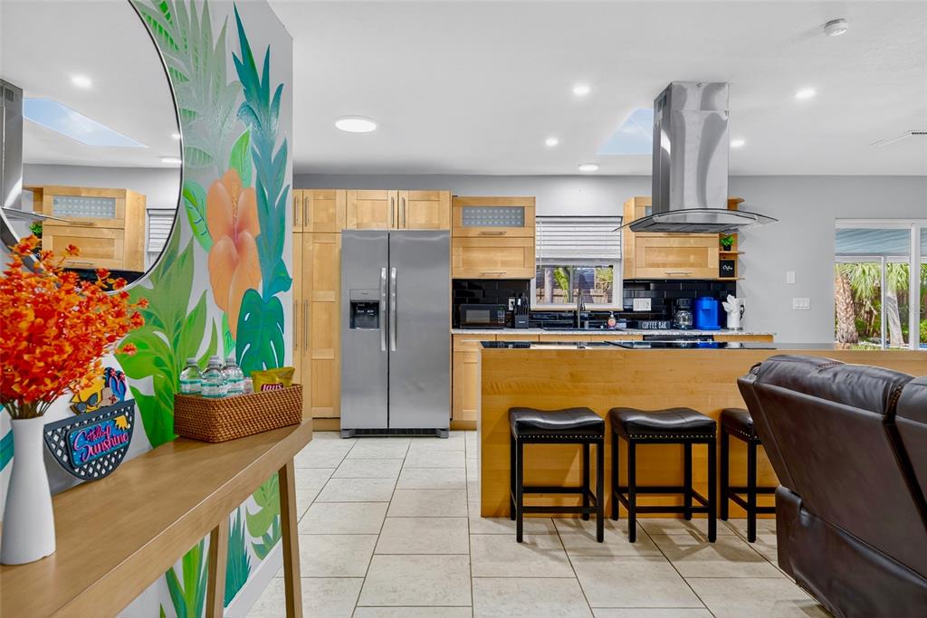 A kitchen features light wood cabinets, stainless steel appliances, a breakfast bar, and tiled floors — 3044 GOLDEN RAIN DRIVE, SARASOTA, FL