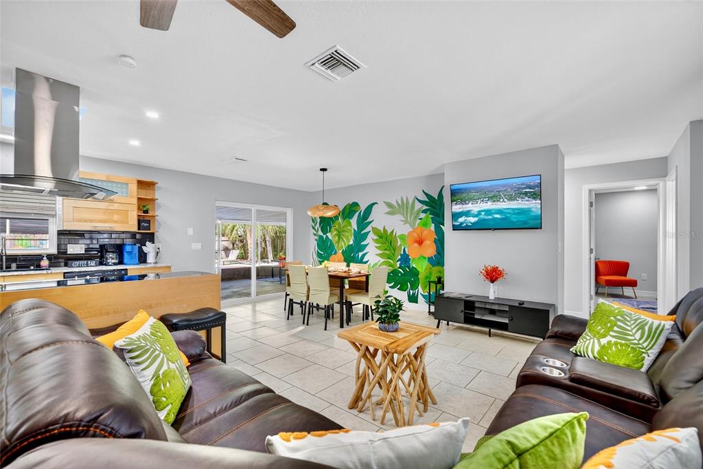 A living room and dining area feature a tropical mural, tile flooring, and leather furniture — 3044 GOLDEN RAIN DRIVE, SARASOTA, FL