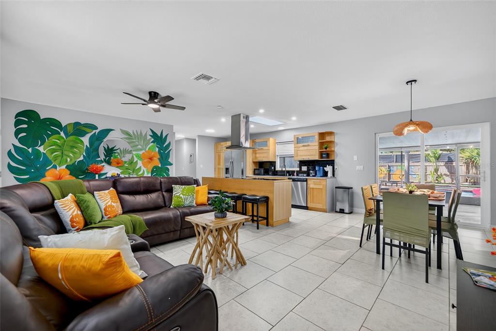 An open-concept living room and kitchen featuring a tropical wall mural and tile flooring — 3044 GOLDEN RAIN DRIVE, SARASOTA, FL