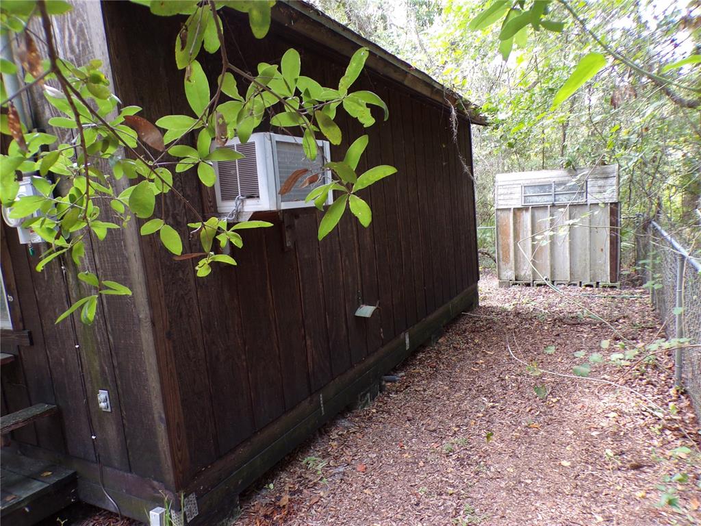 A wooden building exterior features a window air conditioning unit and a small shed nearby — 30 NE 478TH AVENUE, OLD TOWN, FL