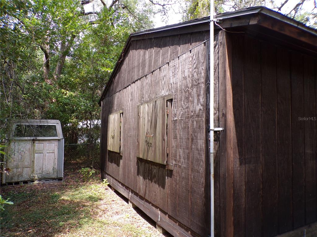 A weathered wooden shed stands in a wooded area next to a small, detached door frame — 30 NE 478TH AVENUE, OLD TOWN, FL