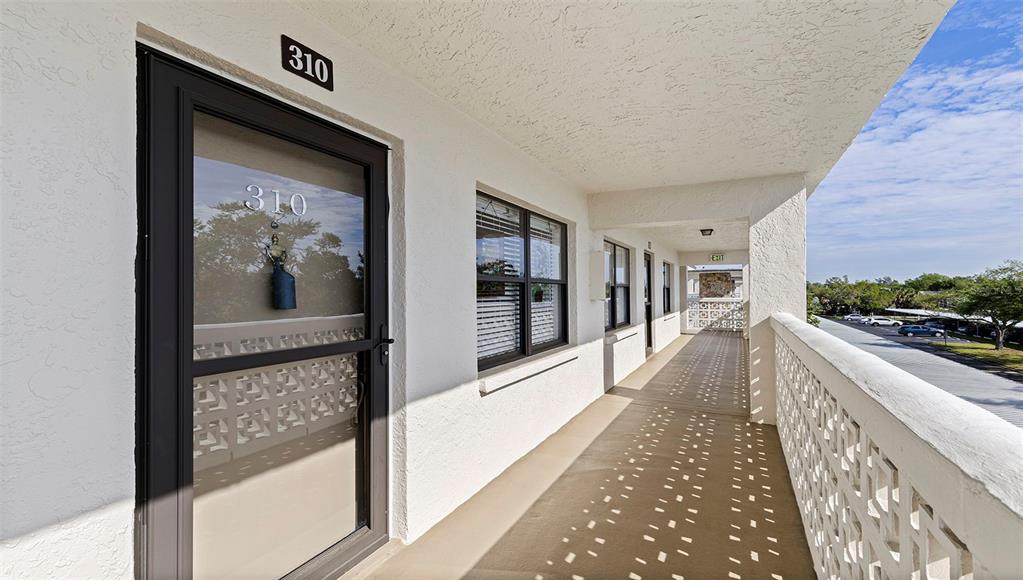 An exterior walkway leads to the entrance of unit 310 with a decorative screen door — 4910 BAY STREET NE UNIT 310, ST PETERSBURG, FL