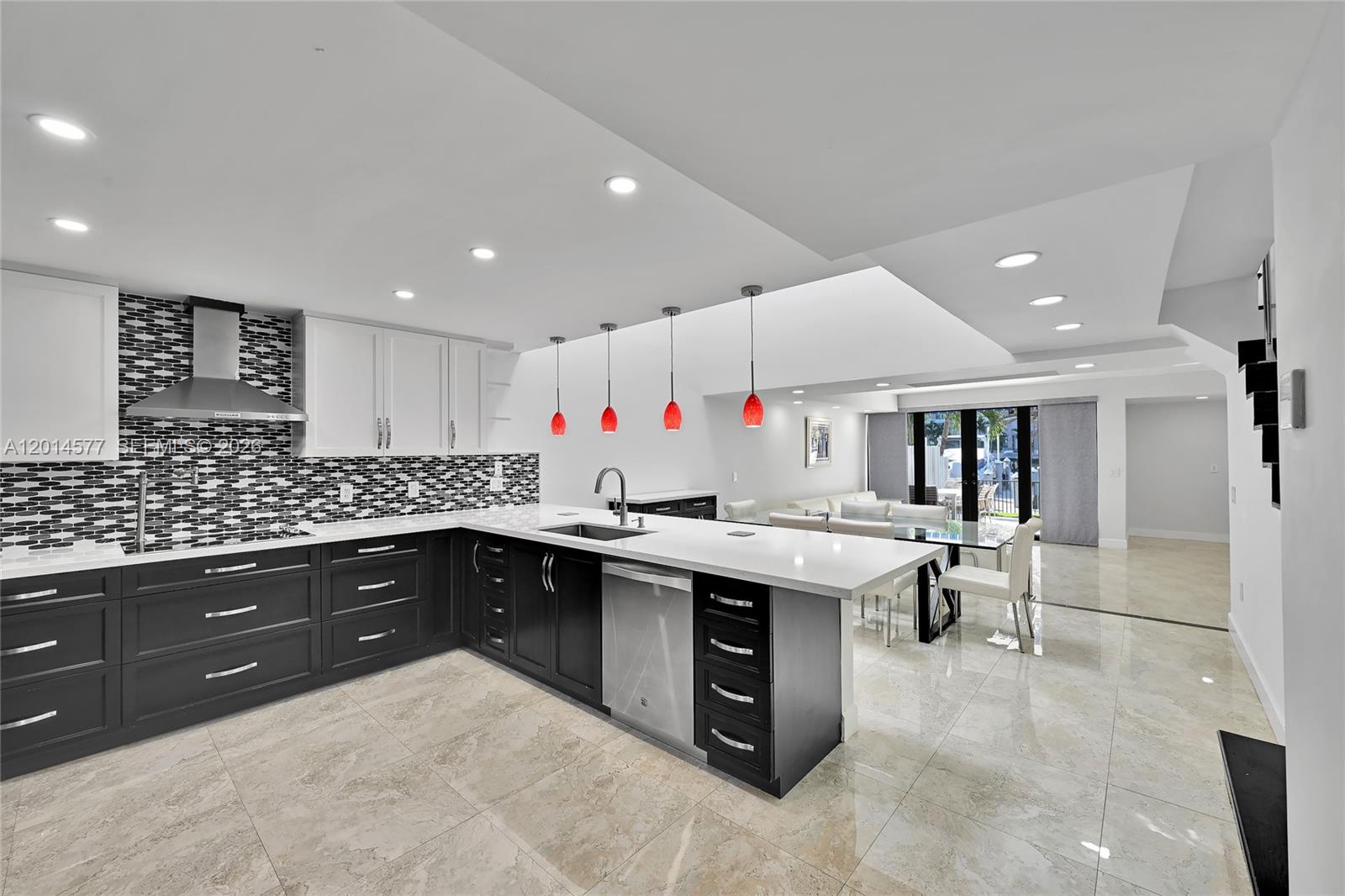 A modern kitchen features dark lower cabinets, white upper cabinets, and a white island — SUNNY ISLES BEACH, FL