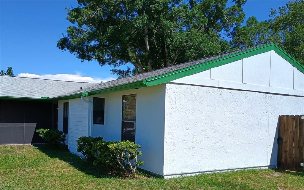The exterior of a white house features a green roof trim and a wooden fence — 602 BAY LAKE TRAIL, OLDSMAR, FL