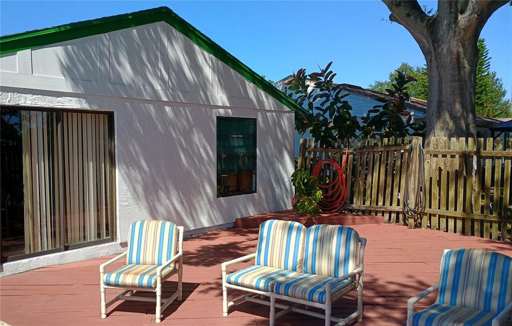 A white house exterior features a red wooden deck with striped patio furniture — 602 BAY LAKE TRAIL, OLDSMAR, FL