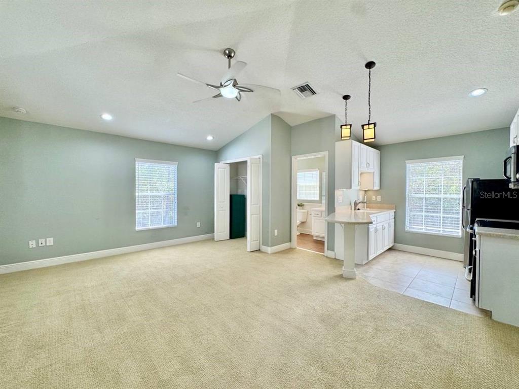 A living room with beige carpeting transitions into a kitchen with tile flooring — 14541 COTSWOLDS DRIVE UNIT B, TAMPA, FL