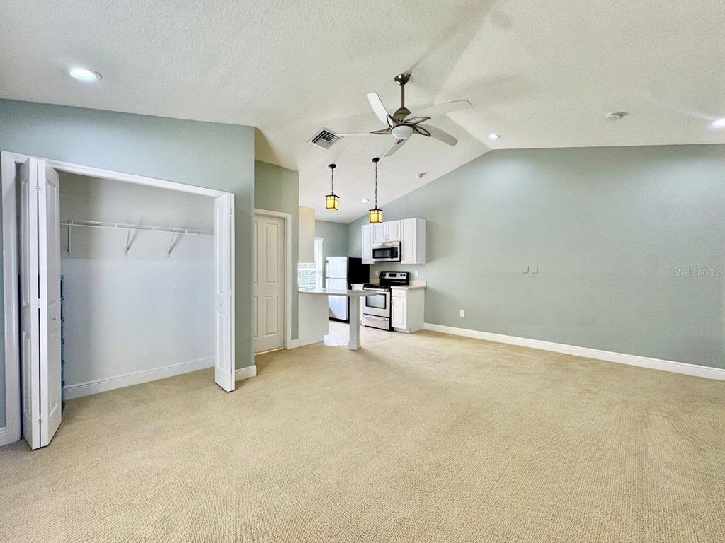 A carpeted living area opens to a kitchen with white cabinets and a breakfast bar — 14541 COTSWOLDS DRIVE UNIT B, TAMPA, FL