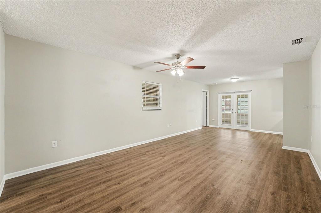 An empty room with light-colored walls, wood-look flooring, a ceiling fan, and glass doors — 2047 SOMERVILLE DRIVE N, LAKELAND, FL