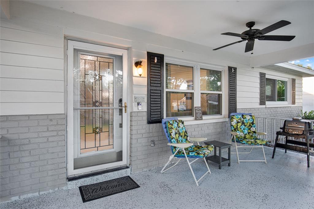 A covered porch features a glass-paneled front door, two floral chairs, and a ceiling fan — 8883 SW 93RD LANE UNIT F, OCALA, FL