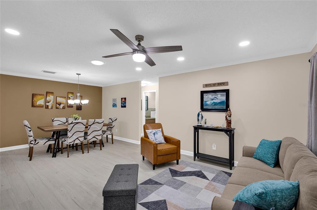 A living and dining area features light wood-look flooring, a ceiling fan, and neutral walls — 8883 SW 93RD LANE UNIT F, OCALA, FL