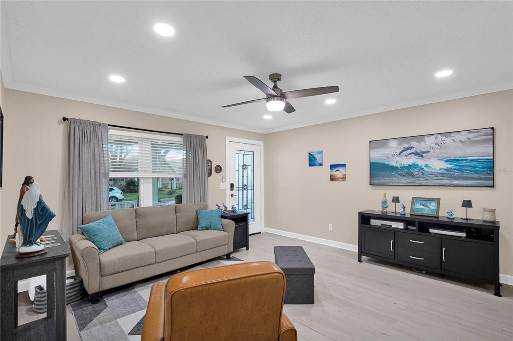 A living room features light wood floors, a beige sofa, and a black media console — 8883 SW 93RD LANE UNIT F, OCALA, FL