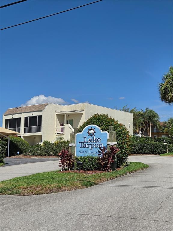 A blue sign for Lake Tarpon Sail & Tennis Club stands before a residential building — 98 S HIGHLAND AVENUE UNIT 2002, TARPON SPRINGS, FL