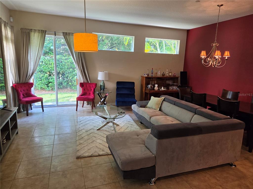 A living and dining room features tile floors, a gray sectional, and a red accent wall — 98 S HIGHLAND AVENUE UNIT 2002, TARPON SPRINGS, FL