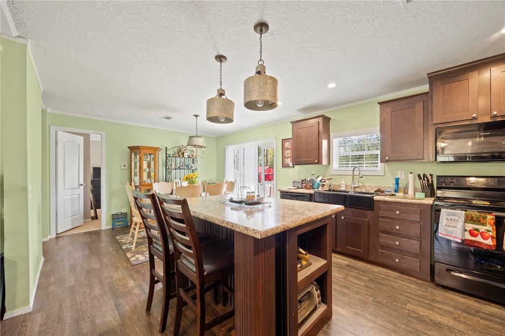 A kitchen features a central island, dark wood cabinets, granite countertops, and light green walls — 221 MAGNOLIA ROAD, HAWTHORNE, FL