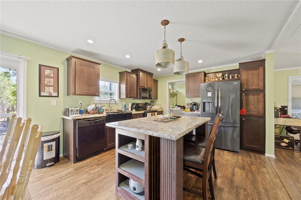 A kitchen features dark wood cabinets, a granite-topped island, and stainless steel appliances — 221 MAGNOLIA ROAD, HAWTHORNE, FL