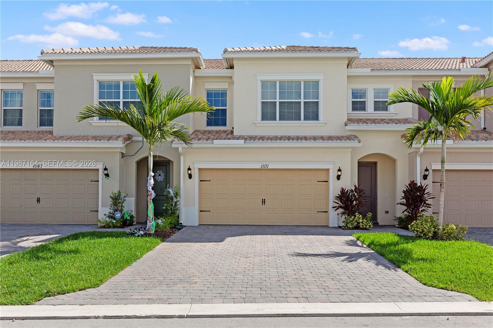 Two beige two-story townhomes with tiled roofs and paved driveways under a blue sky — 1101 Banyan Dr, Hollywood FL 33021, HOLLYWOOD, FL