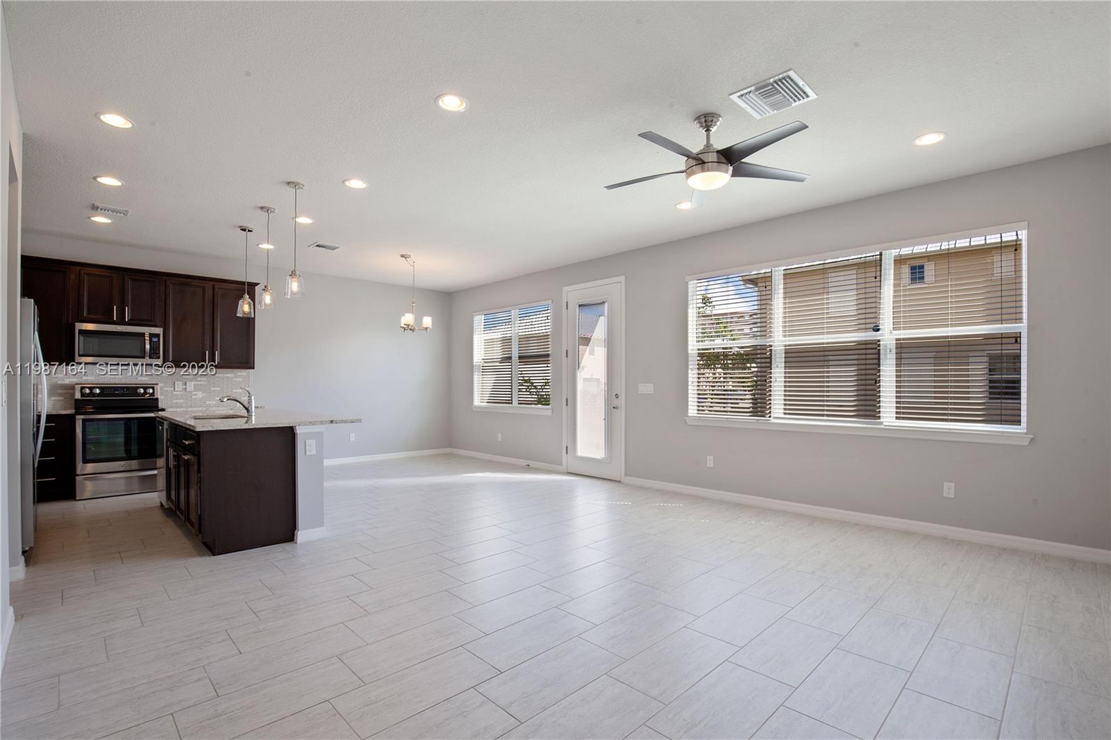 An open-concept living and dining area features a kitchen island, dark cabinetry, and neutral furniture — 1101 Banyan Dr, Hollywood FL 33021, HOLLYWOOD, FL
