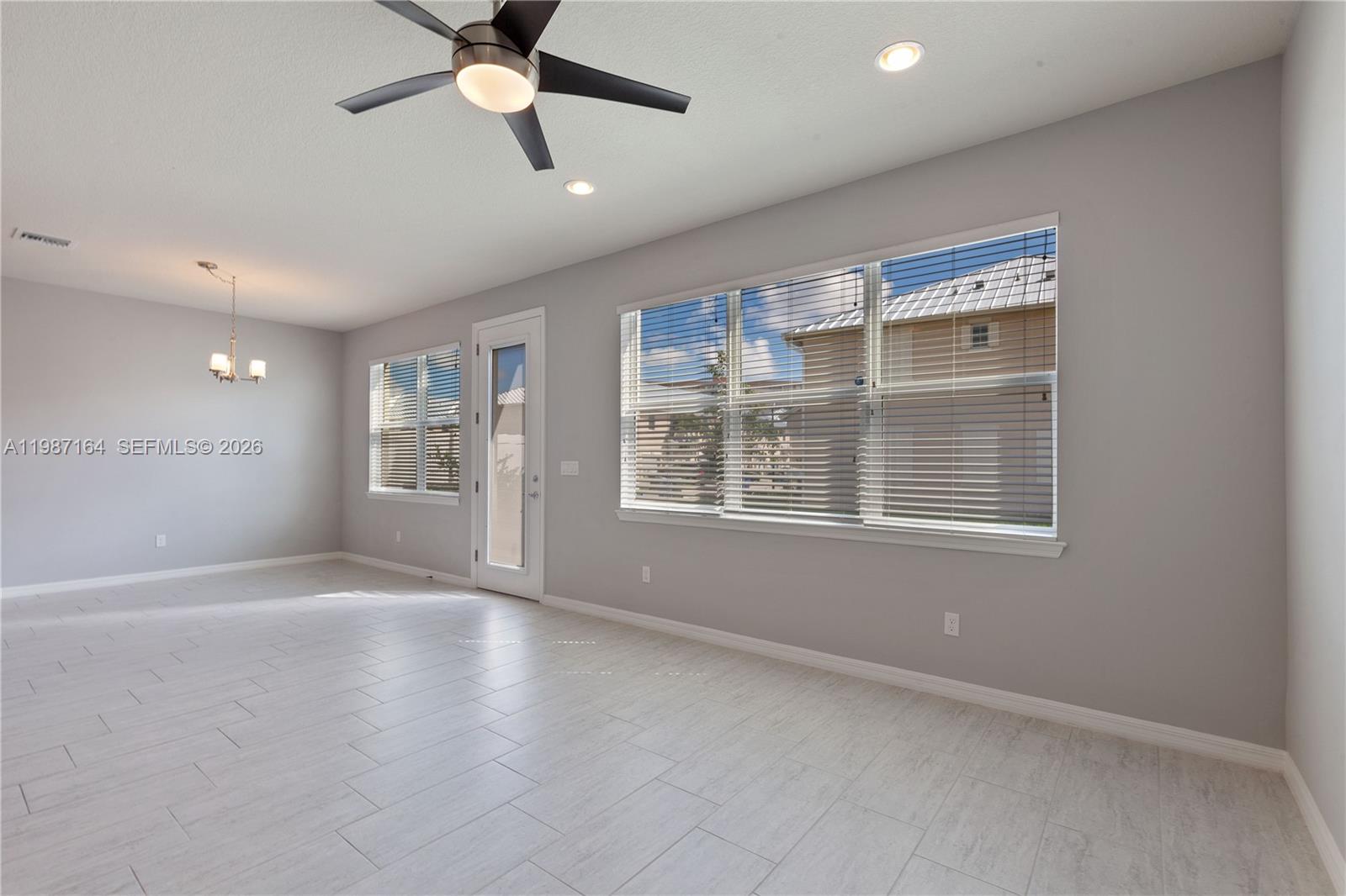 An empty room features light gray walls, tile flooring, a ceiling fan, and large windows — 1101 Banyan Dr, Hollywood FL 33021, HOLLYWOOD, FL