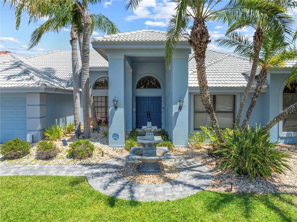 A blue house exterior features a stone fountain, palm trees, and a tiled roof — 5104 E LONGBOAT BOULEVARD, TAMPA, FL