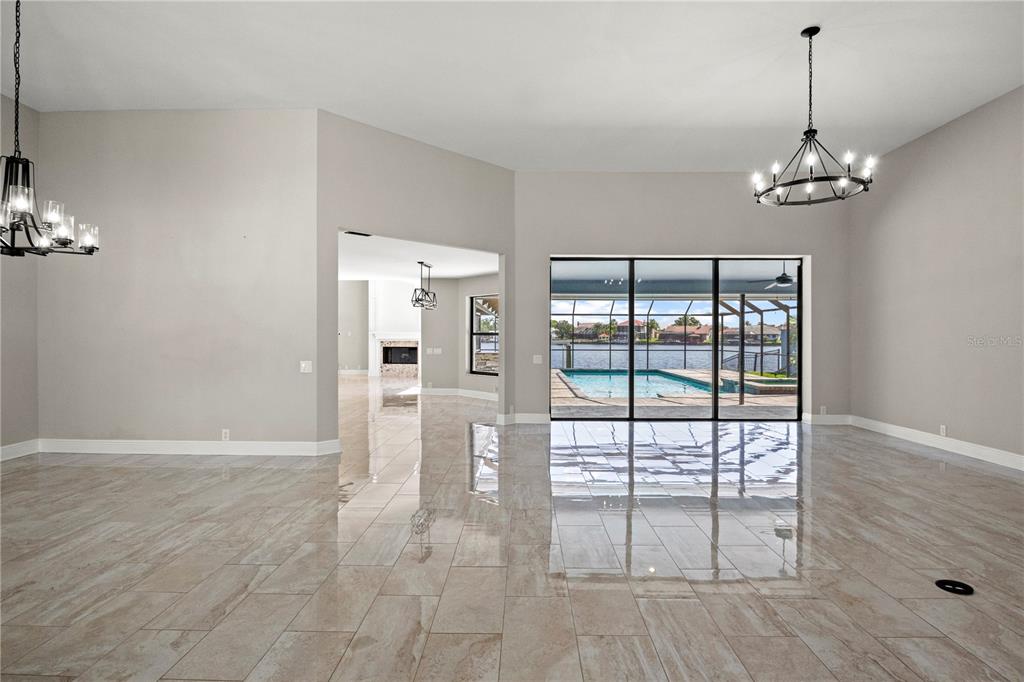 A spacious living area with tile floors, two chandeliers, and sliding doors overlooking a pool — 5104 E LONGBOAT BOULEVARD, TAMPA, FL