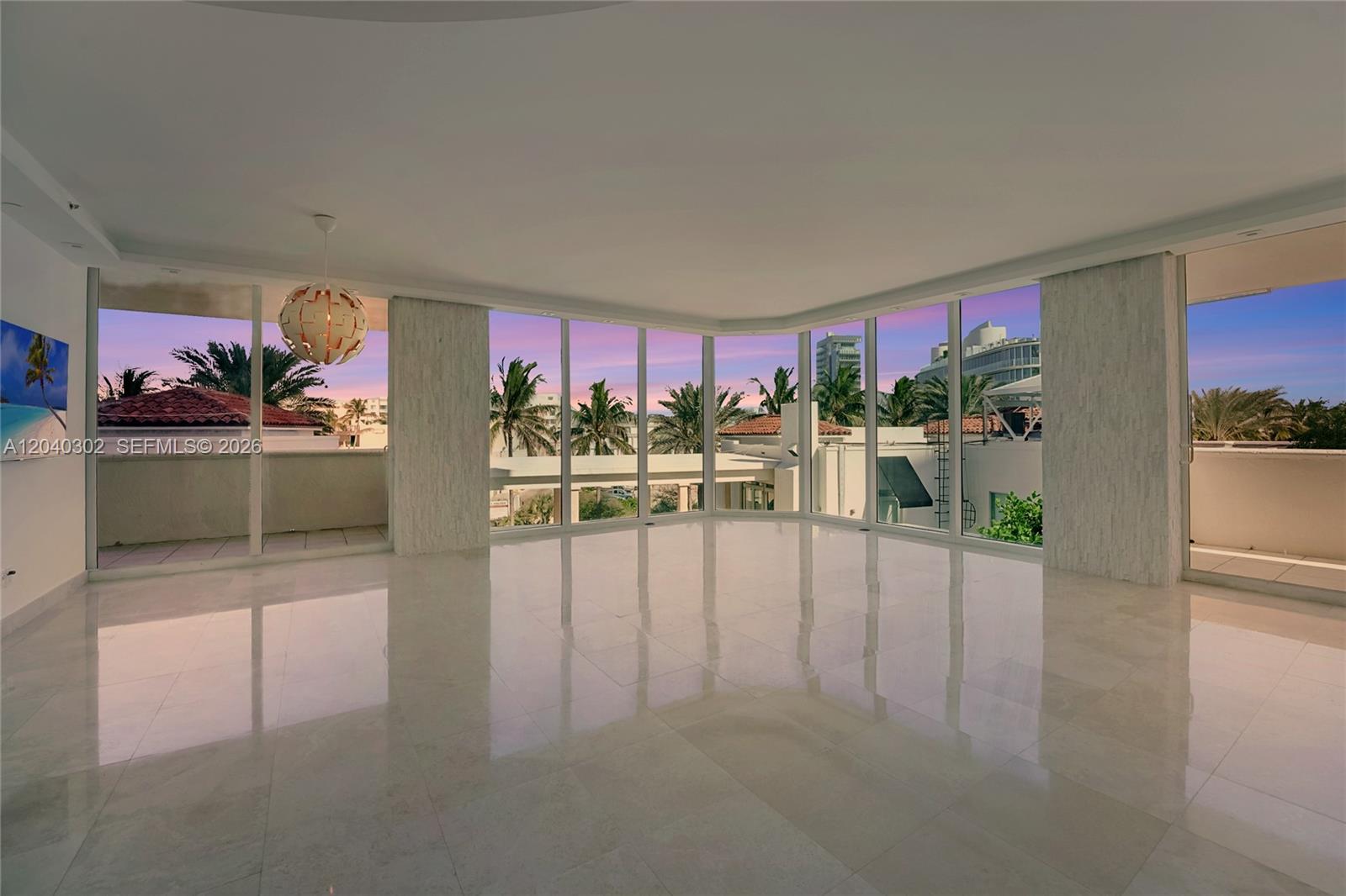 A spacious, empty room features polished tile floors, floor-to-ceiling windows, and a sunset view — 300 S Pointe Dr # 405, Miami Beach FL 33139, MIAMI BEACH, FL