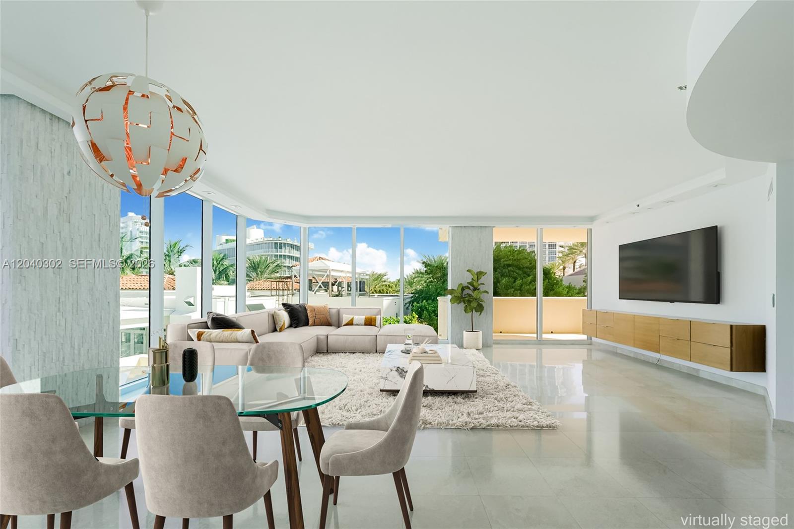 A bright living and dining area features floor-to-ceiling windows, white tile floors, and modern furniture — 300 S Pointe Dr # 405, Miami Beach FL 33139, MIAMI BEACH, FL