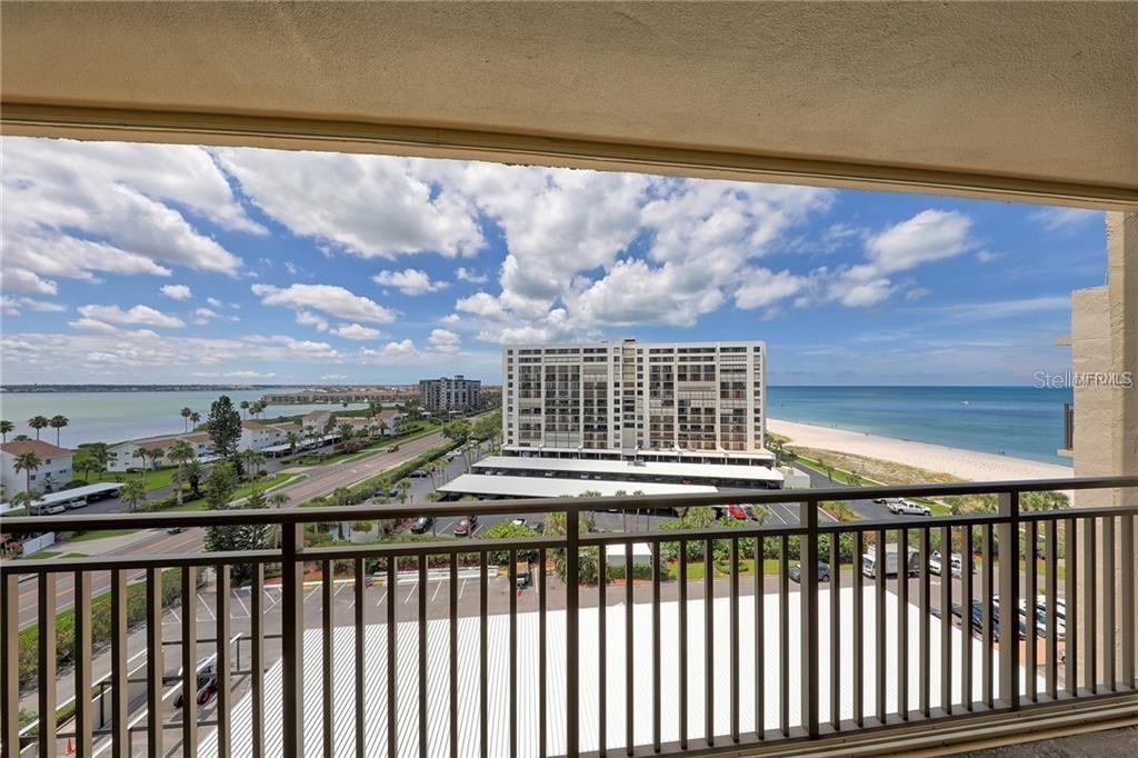 A balcony view overlooks a coastal road, a large apartment building, and the ocean — 1430 GULF BOULEVARD UNIT 806, CLEARWATER, FL