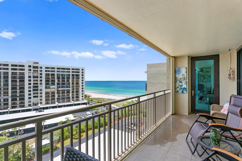 A balcony with metal railings overlooks the beach and ocean next to a large building — 1430 GULF BOULEVARD UNIT 806, CLEARWATER, FL