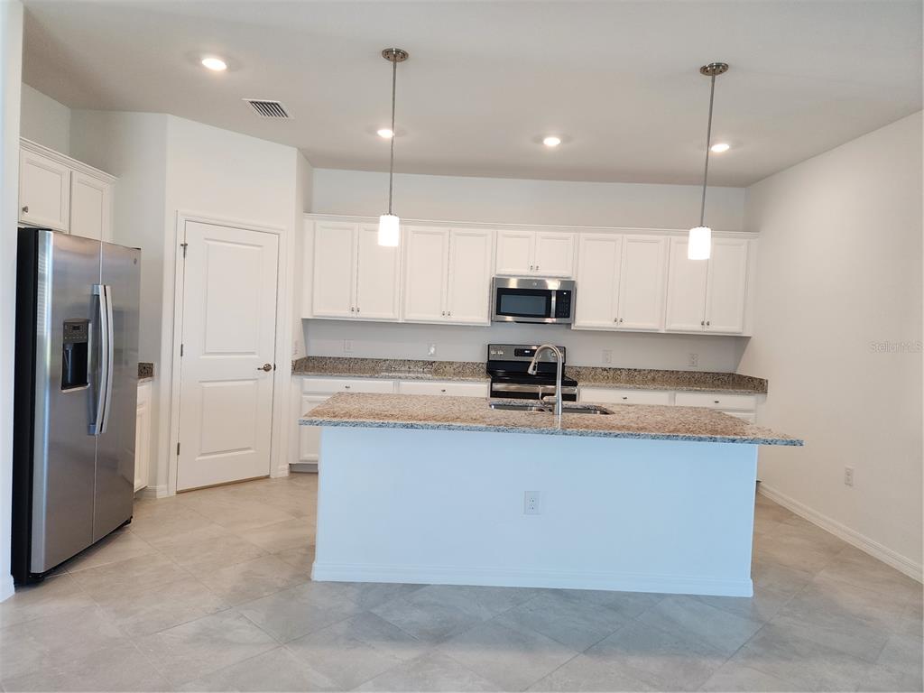 A kitchen with white cabinets, granite countertops, a center island, and stainless steel appliances — 14632 PALAMOS CIRCLE, FORT MYERS, FL