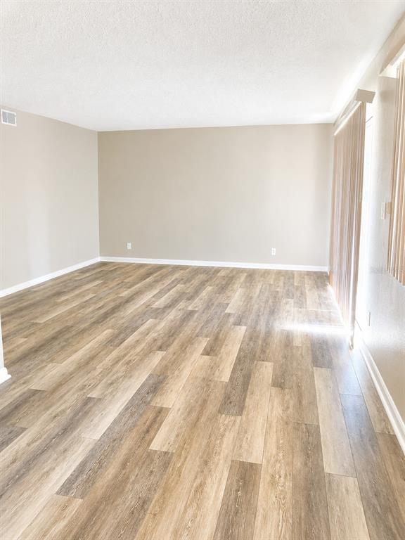 An empty room with light-colored walls and wood-look plank flooring features vertical blinds — 737 MIDWAY DRIVE UNIT A, OCALA, FL