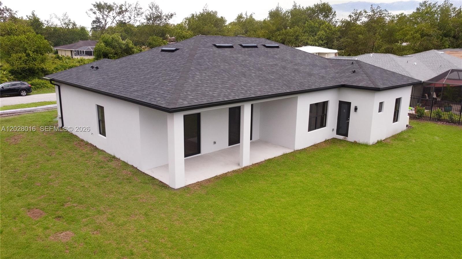 An aerial view of the rear exterior of a white house with a dark roof — 7511 Blutter Rd, North Port FL 34291, NORTH PORT, FL