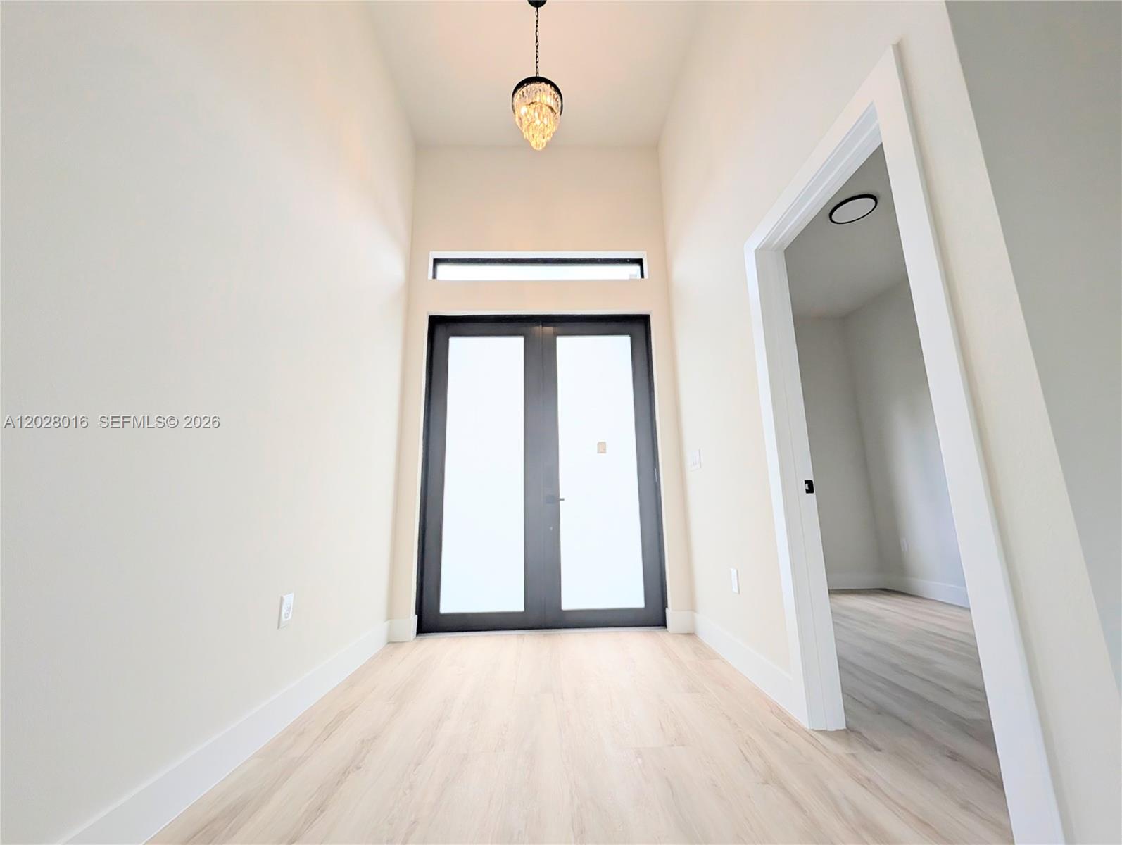 A bright entryway features light wood flooring, a crystal pendant light, and double glass doors — 7511 Blutter Rd, North Port FL 34291, NORTH PORT, FL