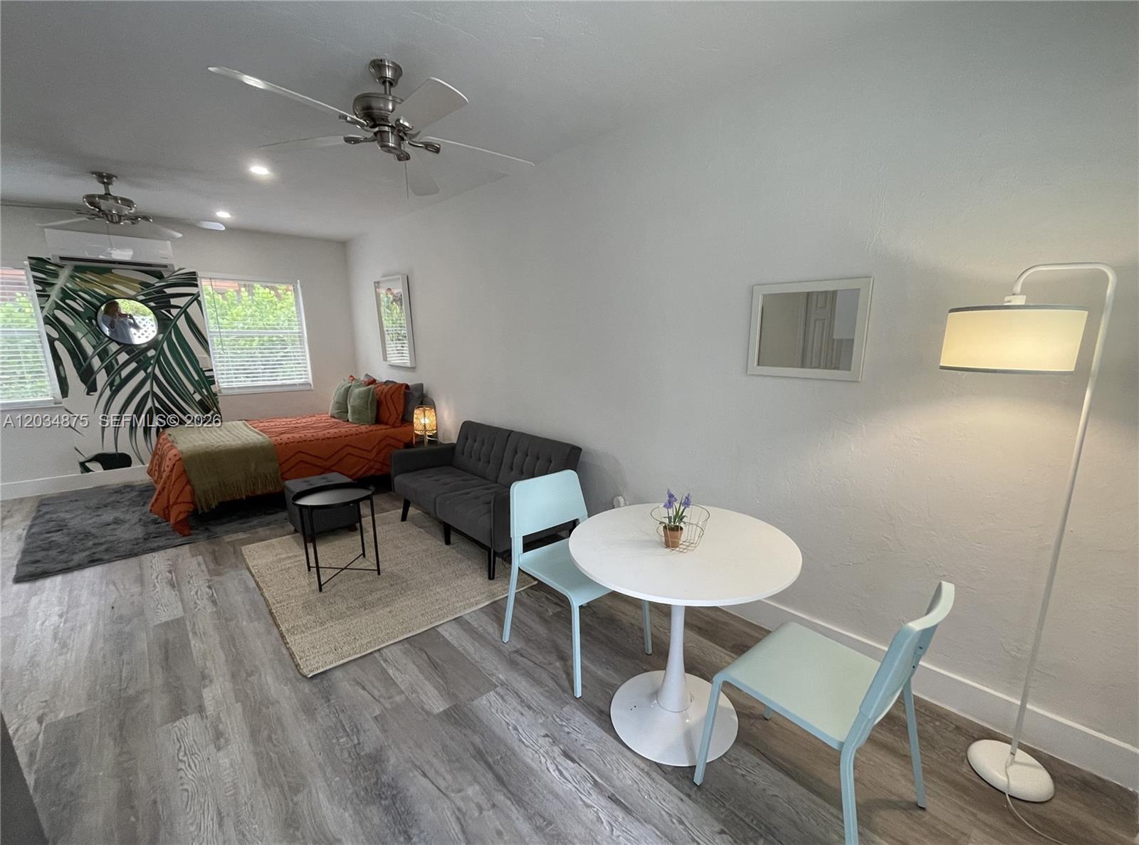 A studio apartment features a bed, a gray sofa, and a small dining table — MIAMI, FL
