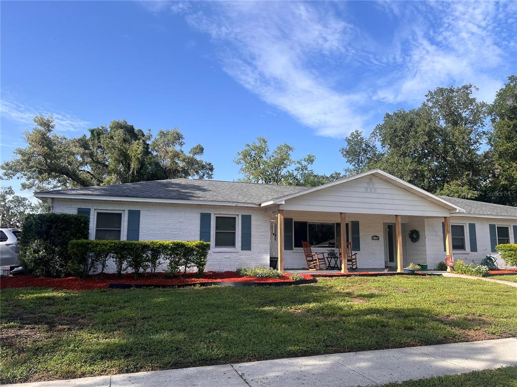 A single-story white brick house with blue shutters sits behind a green lawn — 601 LARRIE ELLEN WAY, BRANDON, FL