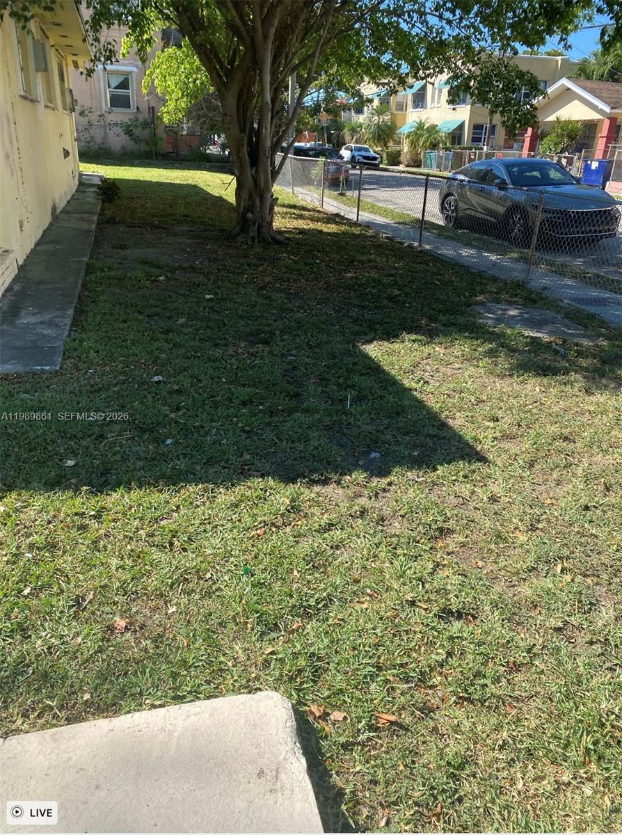 A grassy yard with a large tree sits beside a building and a chain-link fence — 1268 SW 4th St, Miami FL 33135, MIAMI, FL