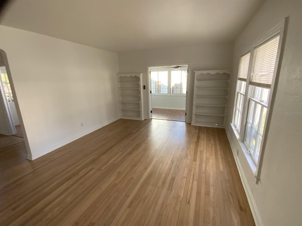 An empty room with hardwood floors, white walls, built-in shelving, and windows with blinds — 608 HIGHLAND AVENUE, ORLANDO, FL