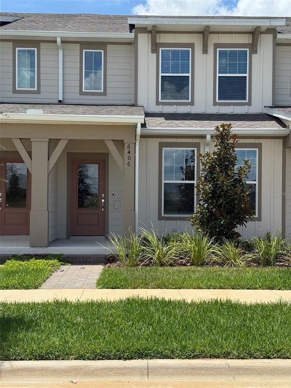 The exterior of a two-story townhouse features light siding, a covered porch, and a front door — 6406 TABEBUIA PARKWAY, WINTER GARDEN, FL