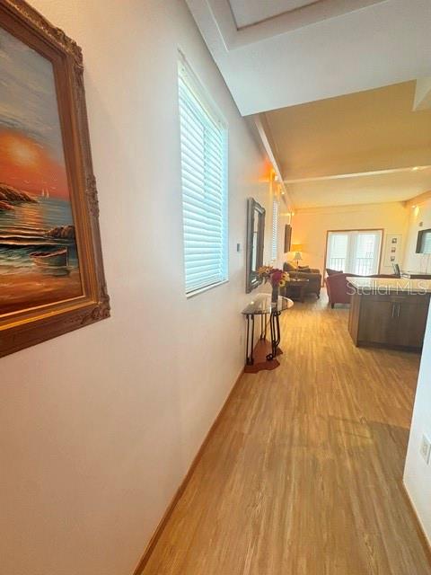A hallway with wood-look flooring leads to an open living area with a kitchen island — 101 PALM HARBOR PARKWAY UNIT B225, PALM COAST, FL